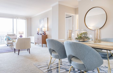 a living room with a table with chairs and a mirror