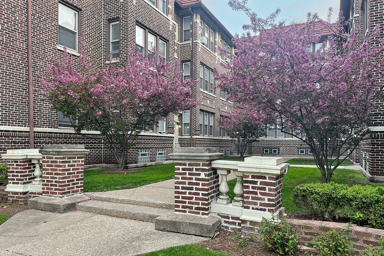 A brick building with a tree with pink flowers in front.