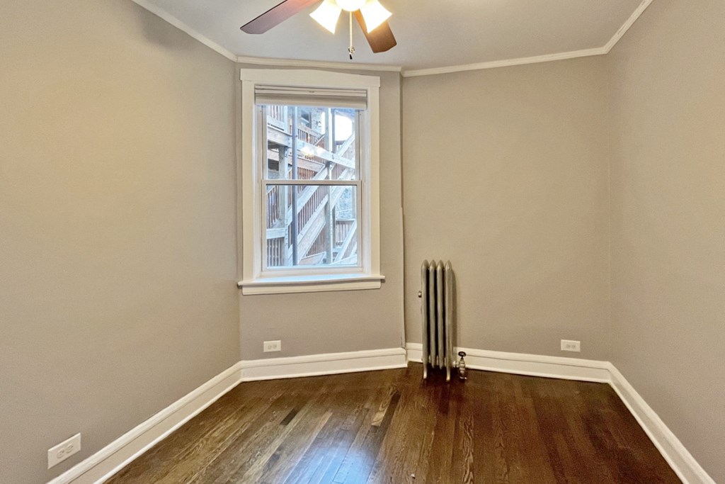 A room with a window and a radiator on the floor.