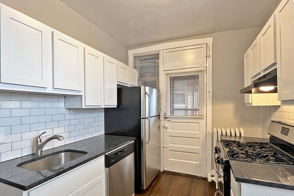 A kitchen with black countertops and white cabinets.