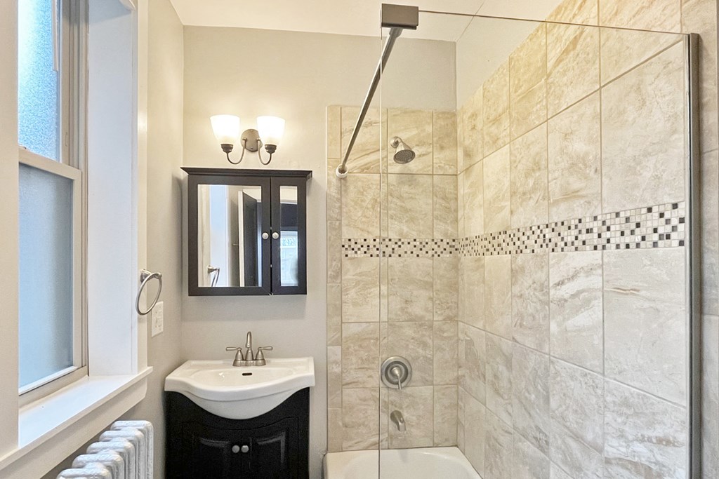 A bathroom with a white sink and a shower with a black and white tile.