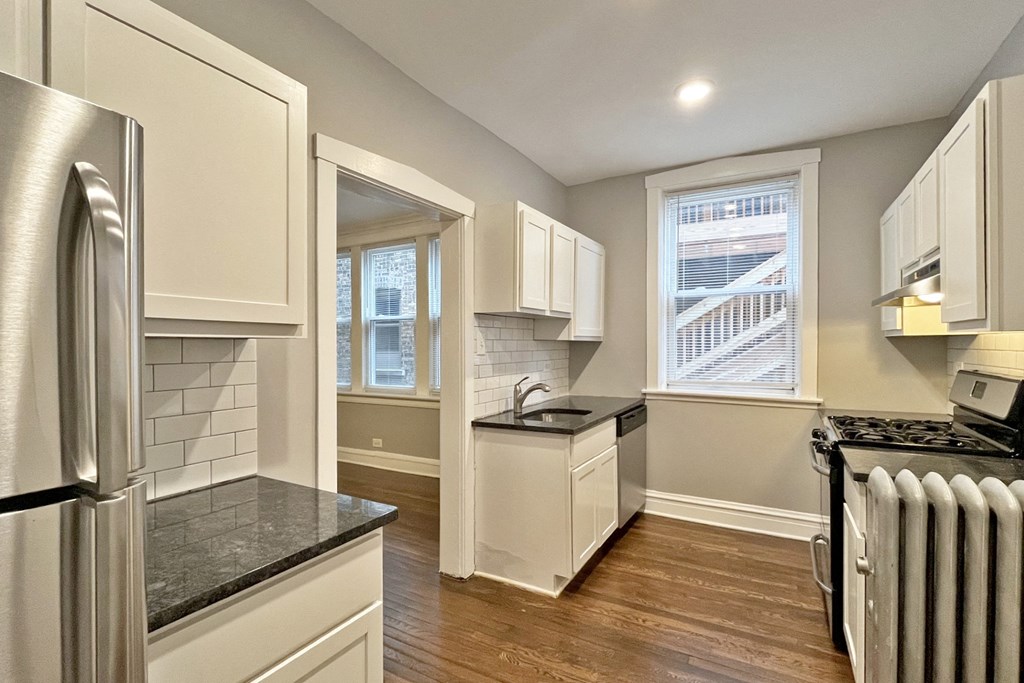 A kitchen with a black countertop and white cabinets.