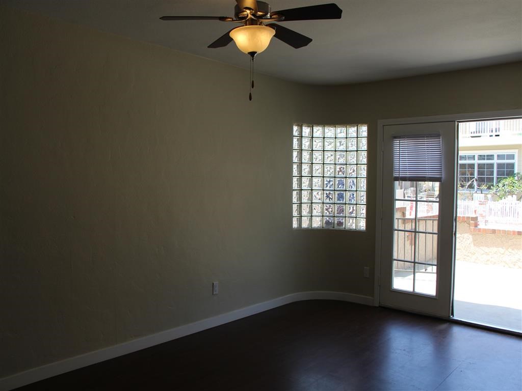 an empty living room with a ceiling fan and a window