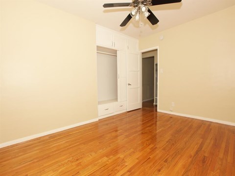 an empty living room with wood floors and a ceiling fan