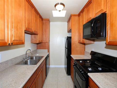 a kitchen with wood cabinets and black appliances and a sink