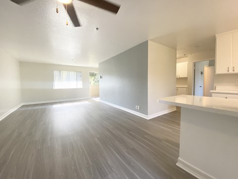 an empty living room and kitchen with a ceiling fan