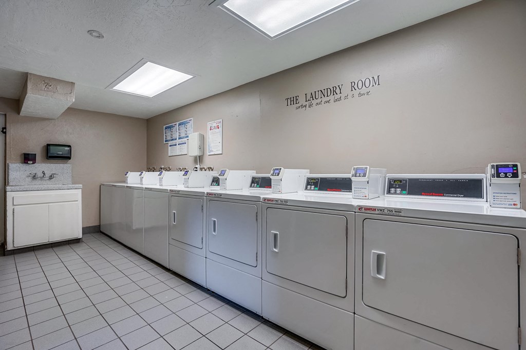 the laundry room is equipped with washers and dryers and a row of machines