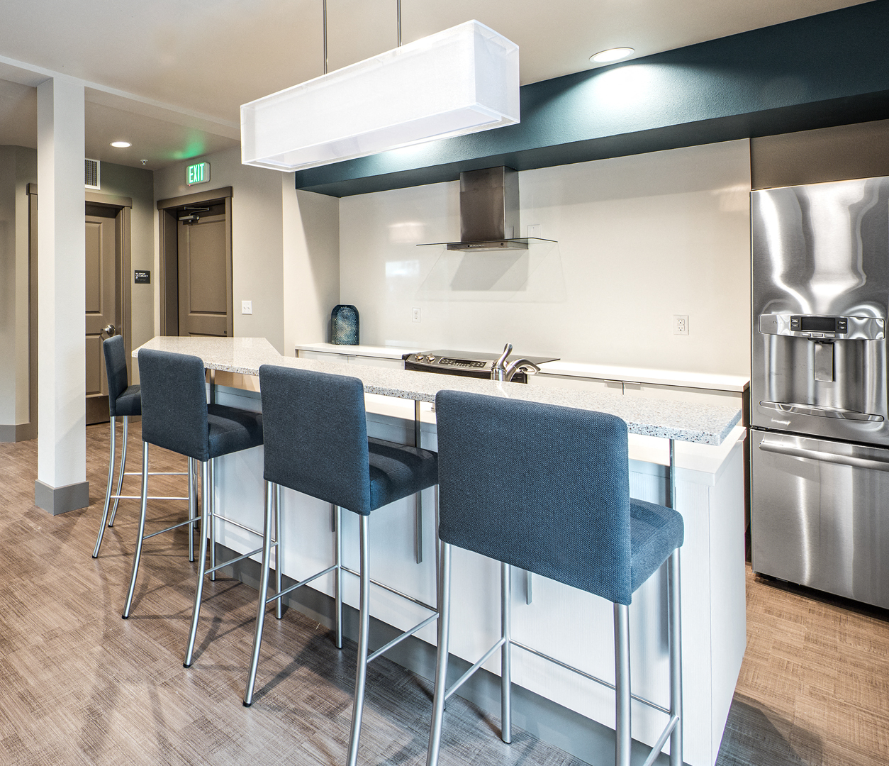 a kitchen with a bar and stools and a stainless steel refrigerator