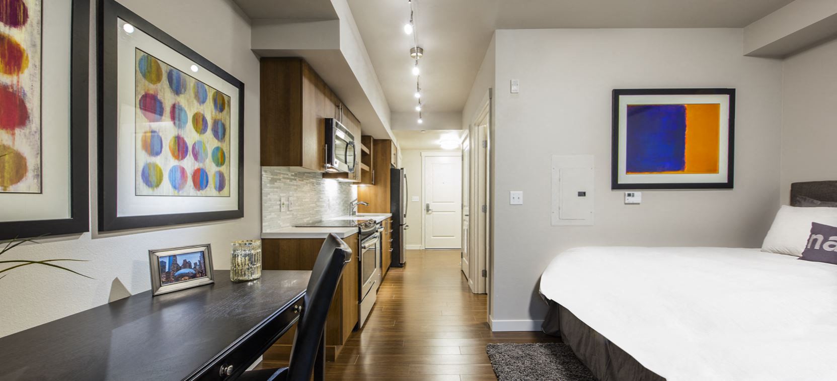 a bedroom with a bed and a desk and a kitchen