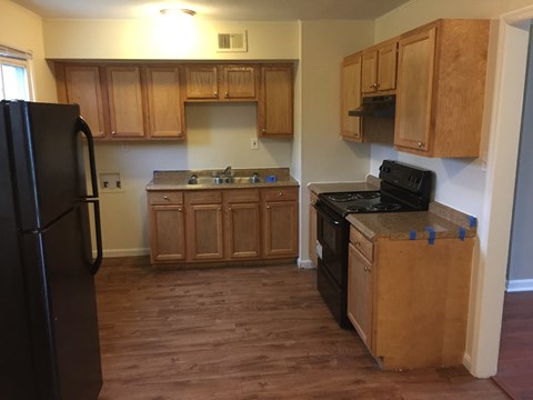 A kitchen with wooden cabinets and a black refrigerator.