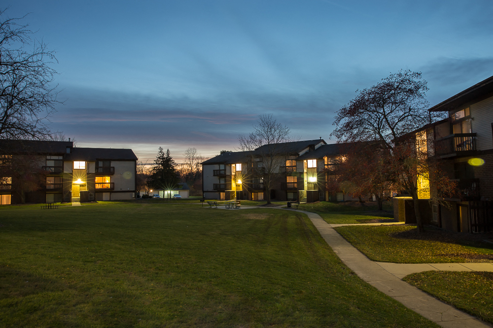 a row of houses at night with the lights on in the yard