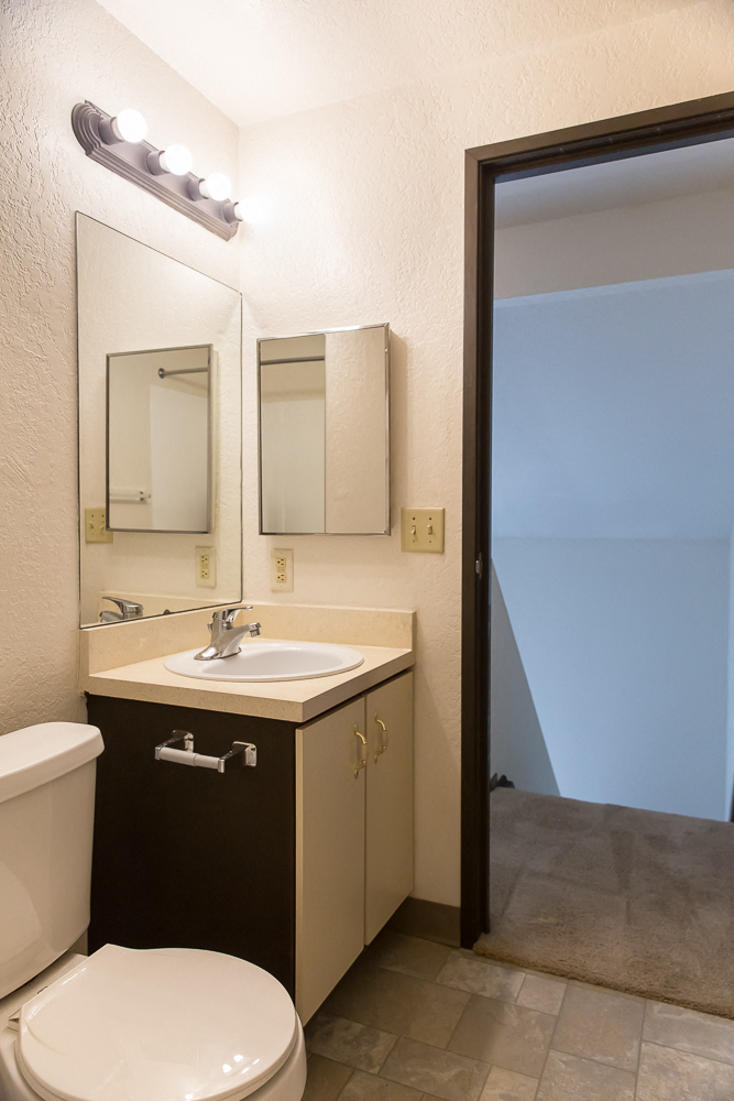 a bathroom with a toilet sink and mirror and a shower
