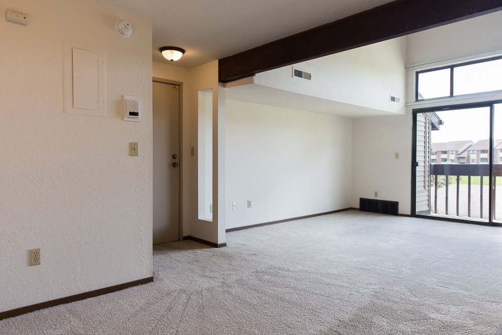 the living room of an empty apartment with a large window