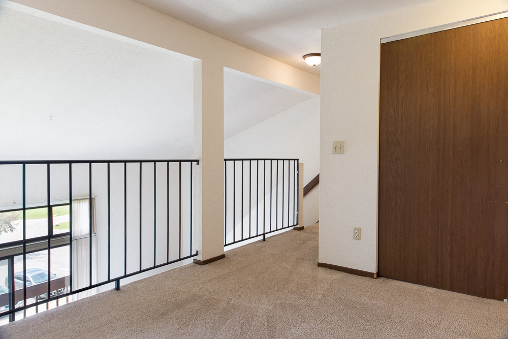 an empty living room with a railing and a door to a balcony