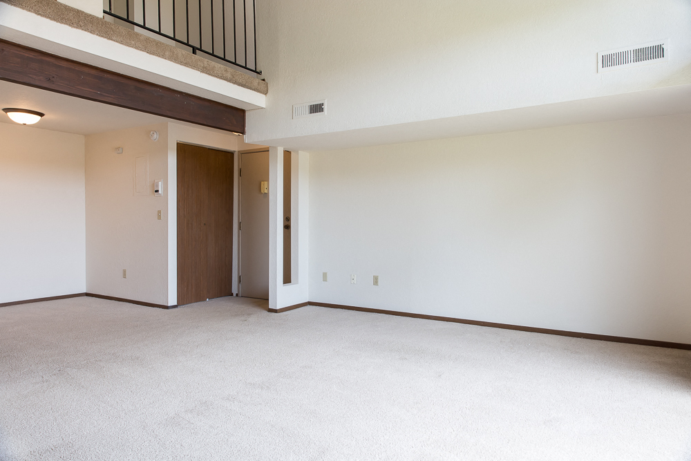 the living room of an empty house with white walls and a wooden door