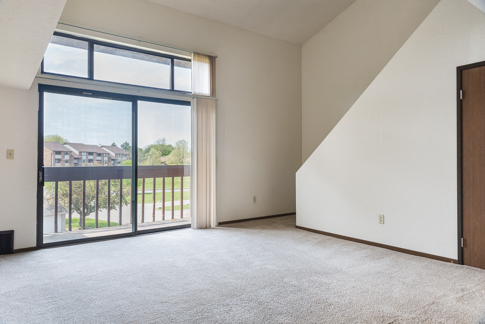 an empty living room with a balcony and sliding glass doors