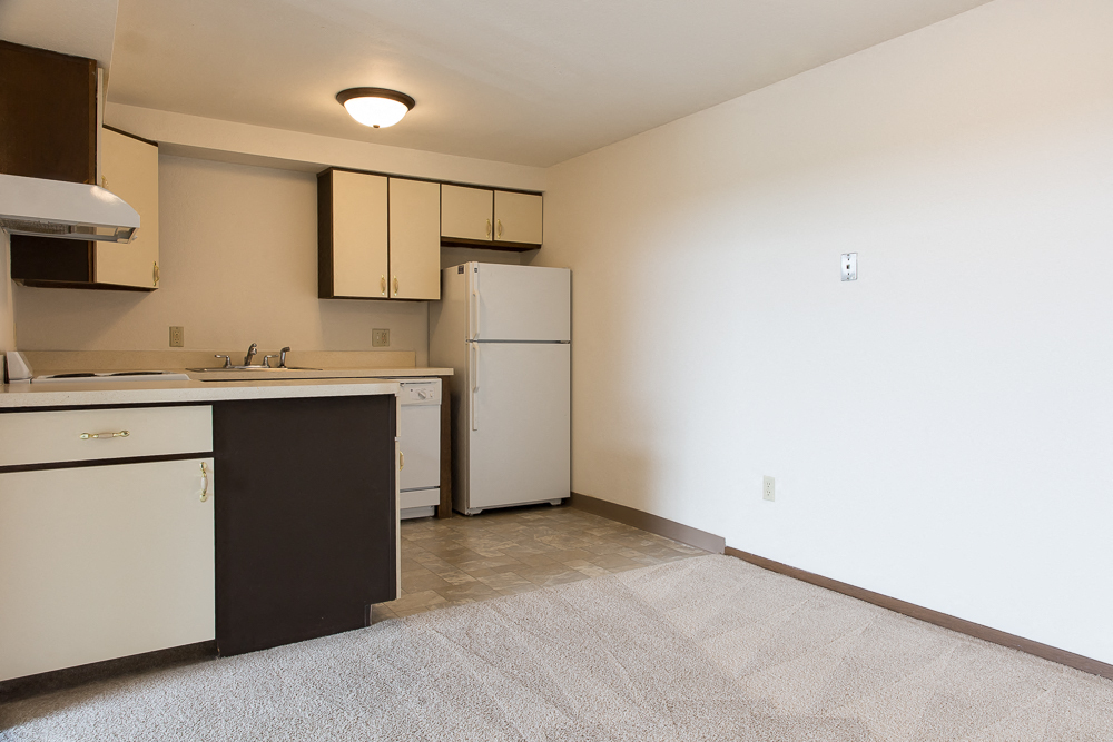 an empty kitchen with white appliances and a refrigerator and sink