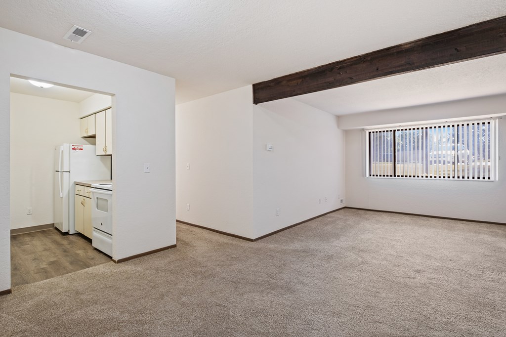 A kitchen with white appliances and a window with blinds.