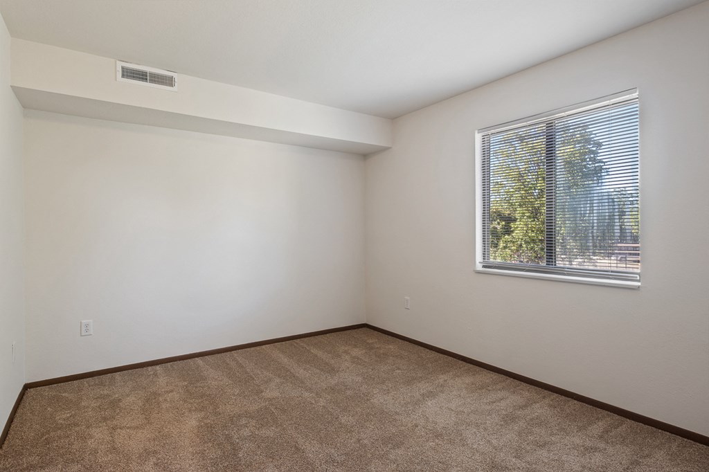 A room with a window and carpeted floor.