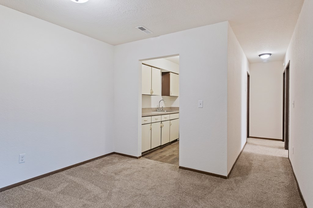 A kitchen area with white walls and a carpeted floor.