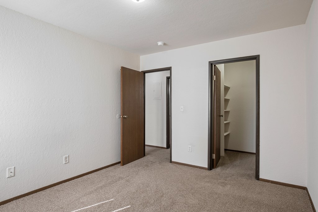 A room with a carpeted floor and two open doors.