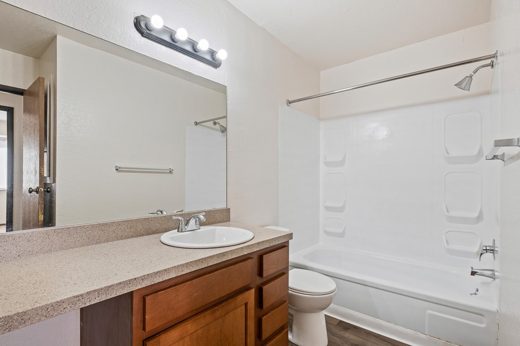 A white bathroom with a sink, mirror, and bathtub.