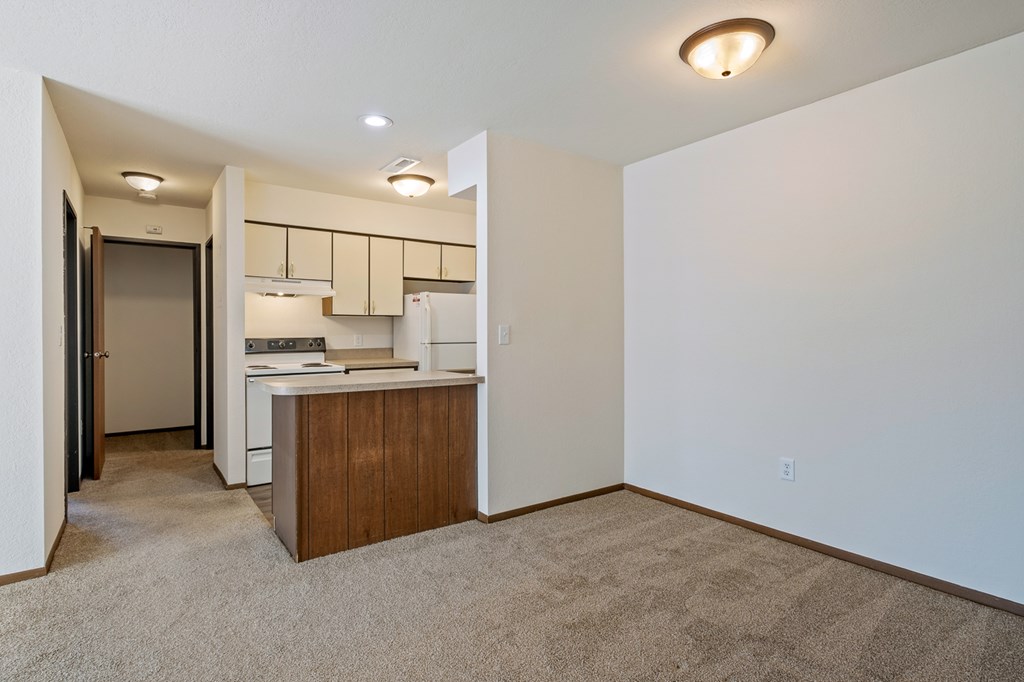 A kitchen area with a refrigerator, sink, and cabinets.