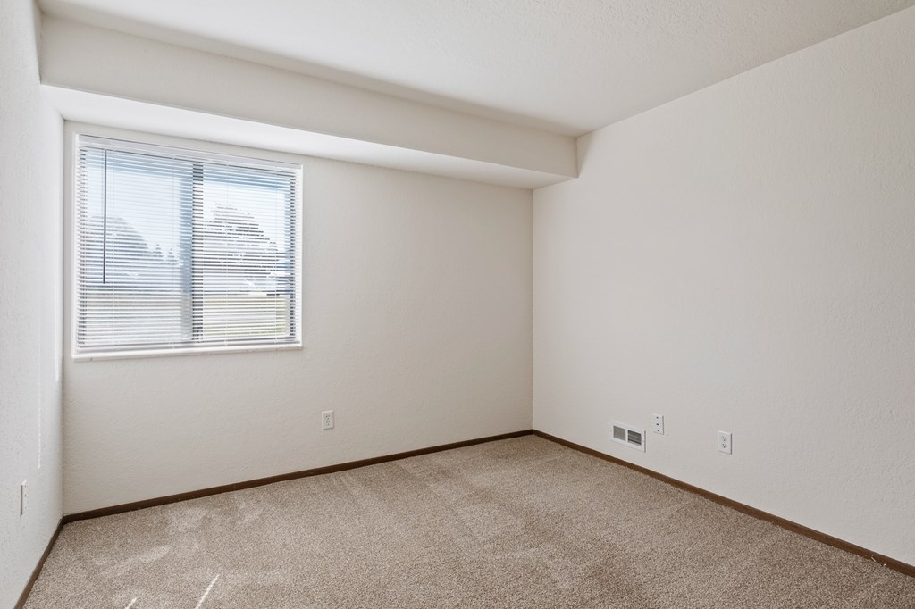 A room with a window and carpeted floor.