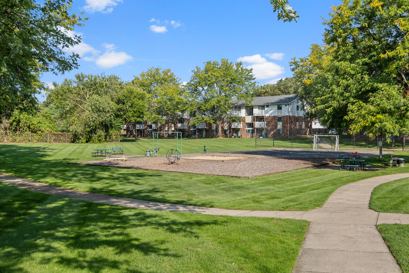 A park with a playground and a building in the background.
