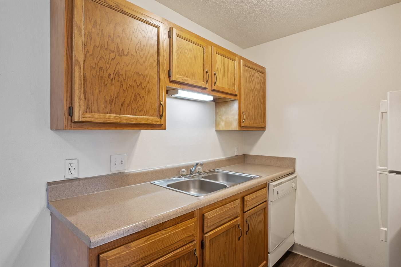A kitchen with wooden cabinets and a white refrigerator.