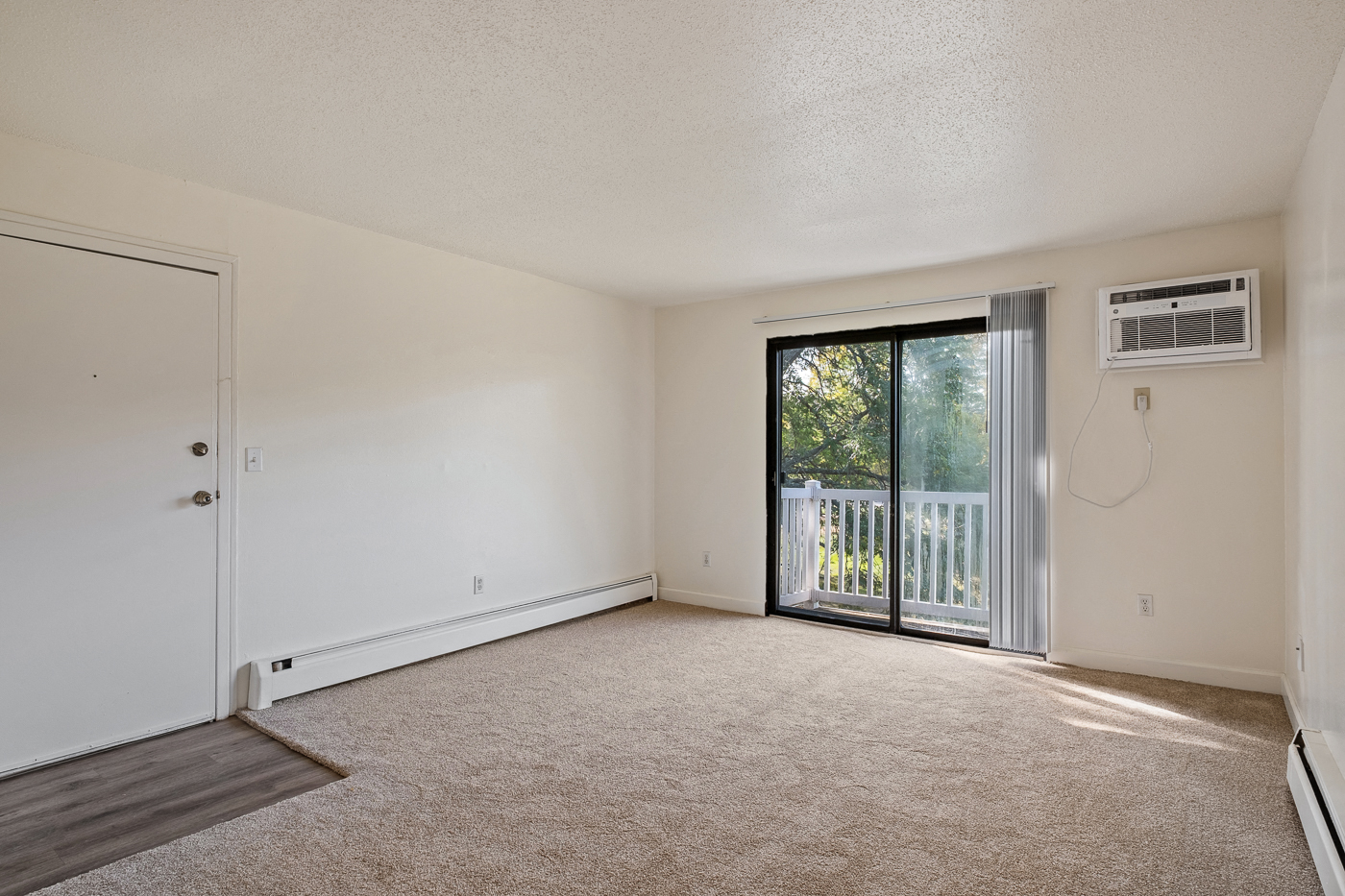 A room with a sliding glass door leading to a balcony.