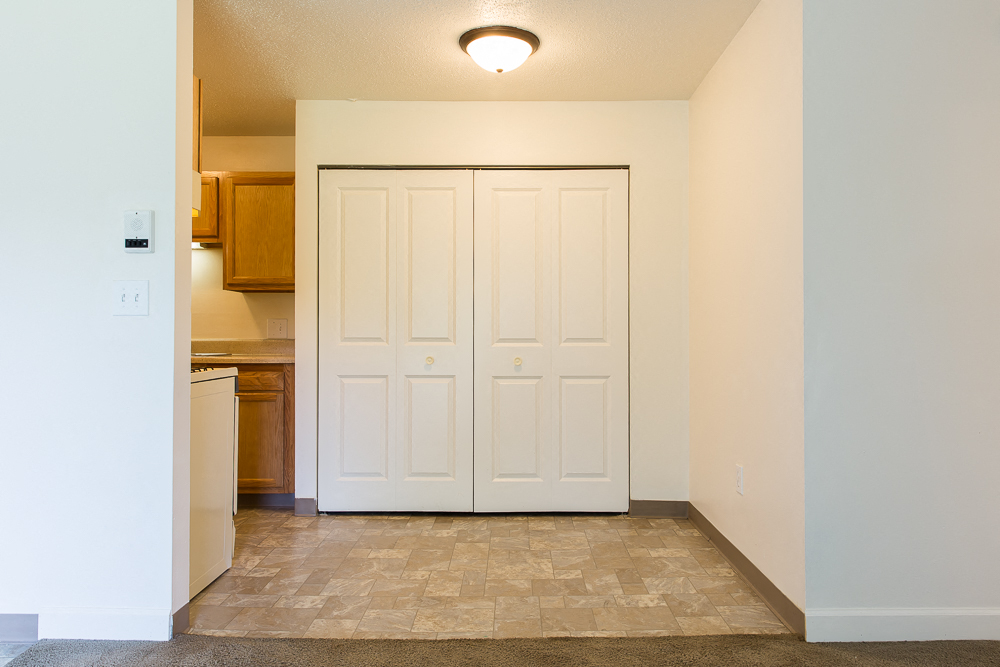 an empty living room with two closets and a kitchen
