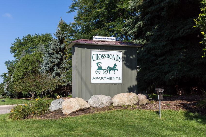 a sign for crossroads apartments in front of a green shed with rocks