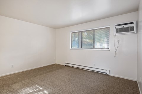 A room with a window and a wall-mounted air conditioner.