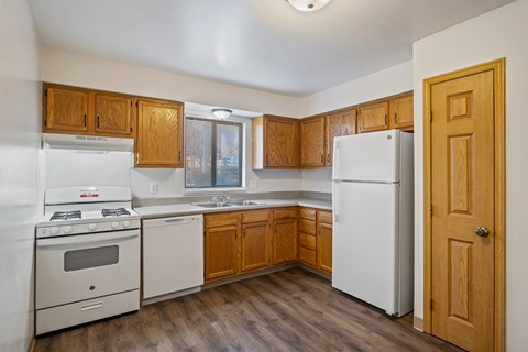 A kitchen with white appliances and wooden cabinets.