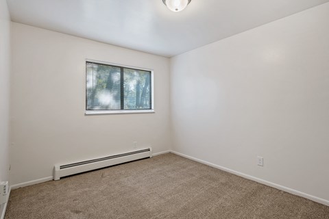 A room with a window and a heater on the wall.