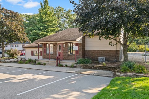 A small building with a red door is surrounded by a parking lot.