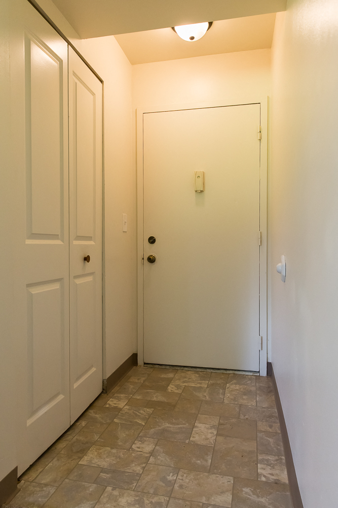 a hallway with white walls and a white door and a tile floor
