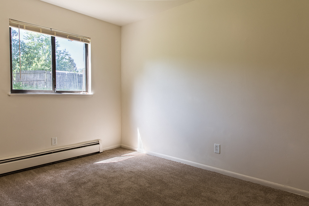 an empty room with a window and a carpet