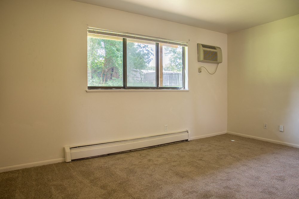 an empty room with a window and an air conditioner