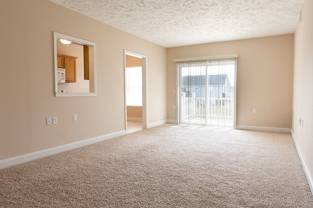 A spacious room with a carpeted floor and a large window.