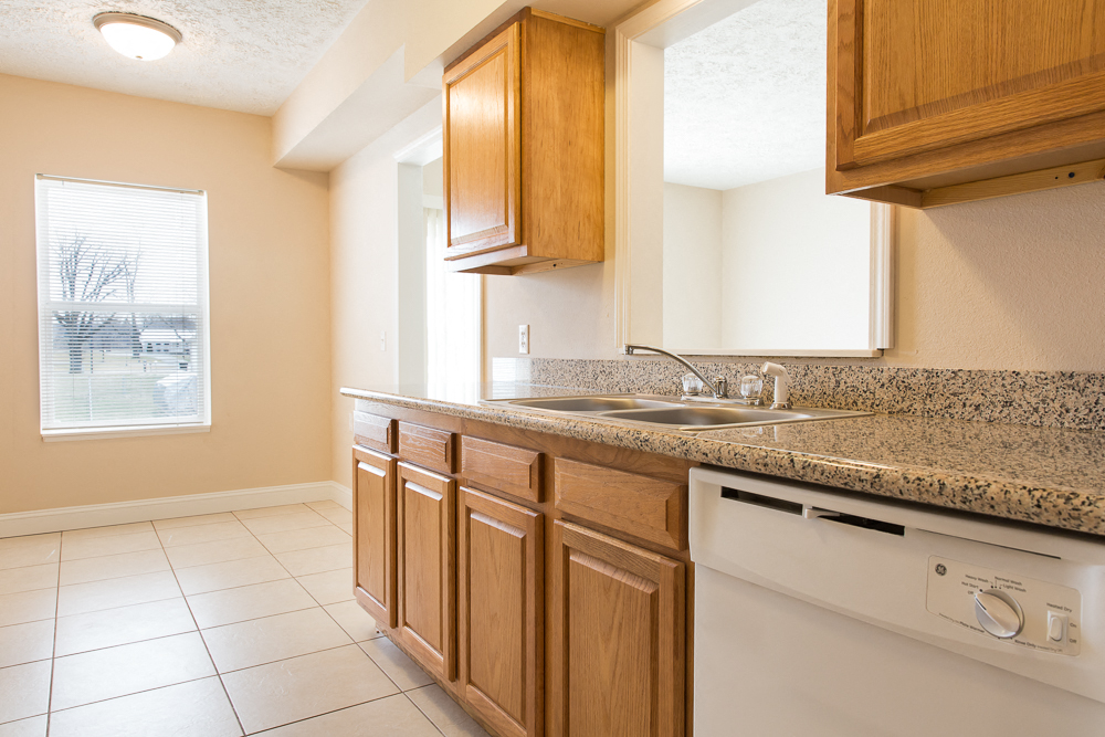 A kitchen with a white dishwasher and wooden cabinets.