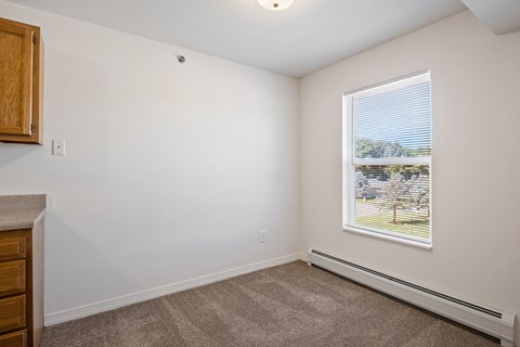 A room with a window showing a view of a tree and a building outside.