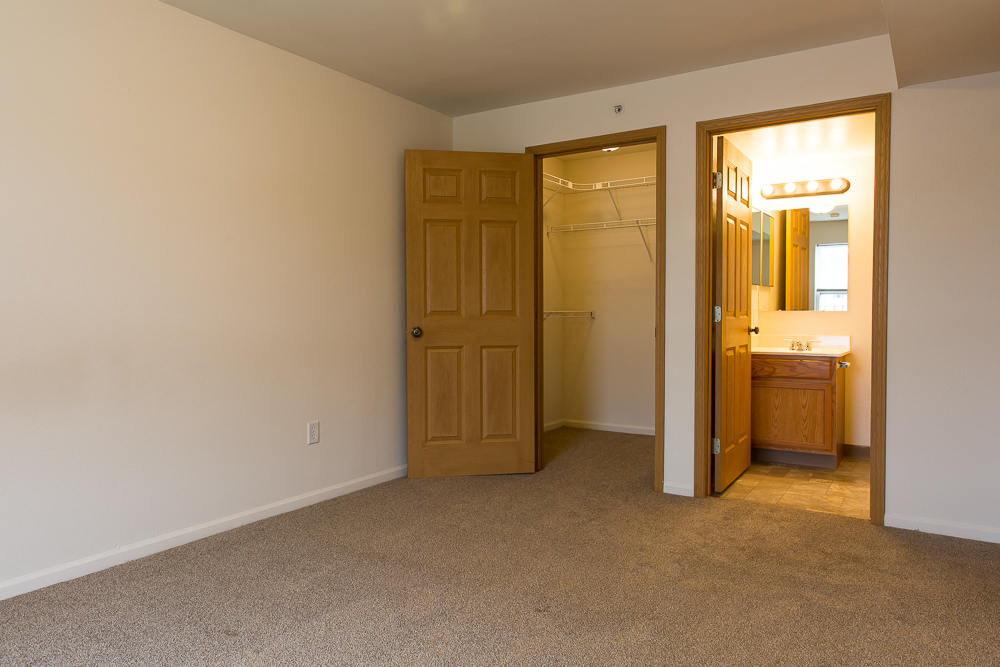an empty room with a bathroom and a door to a closet
