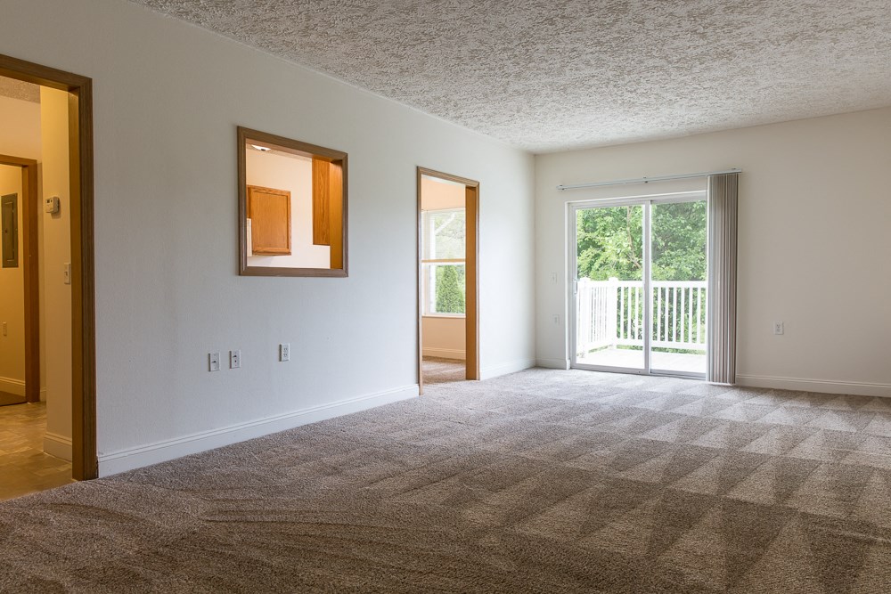 an empty living room with a door to a balcony