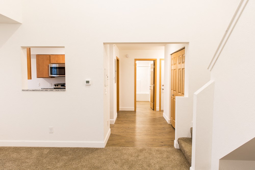 a hallway of a home with a kitchen and a hallway to a living room