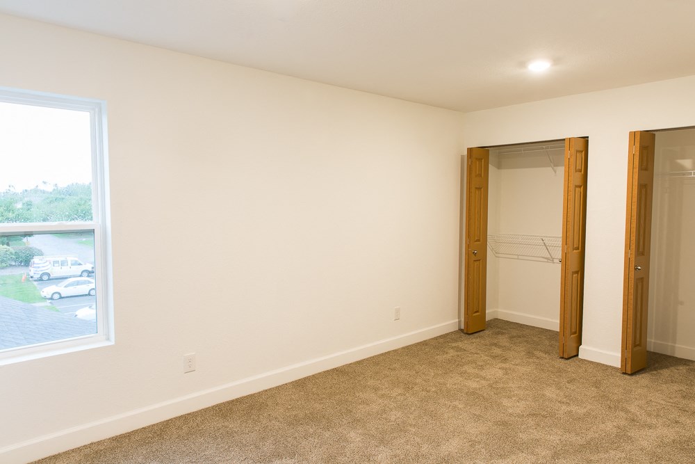 an empty room with a window and a closet