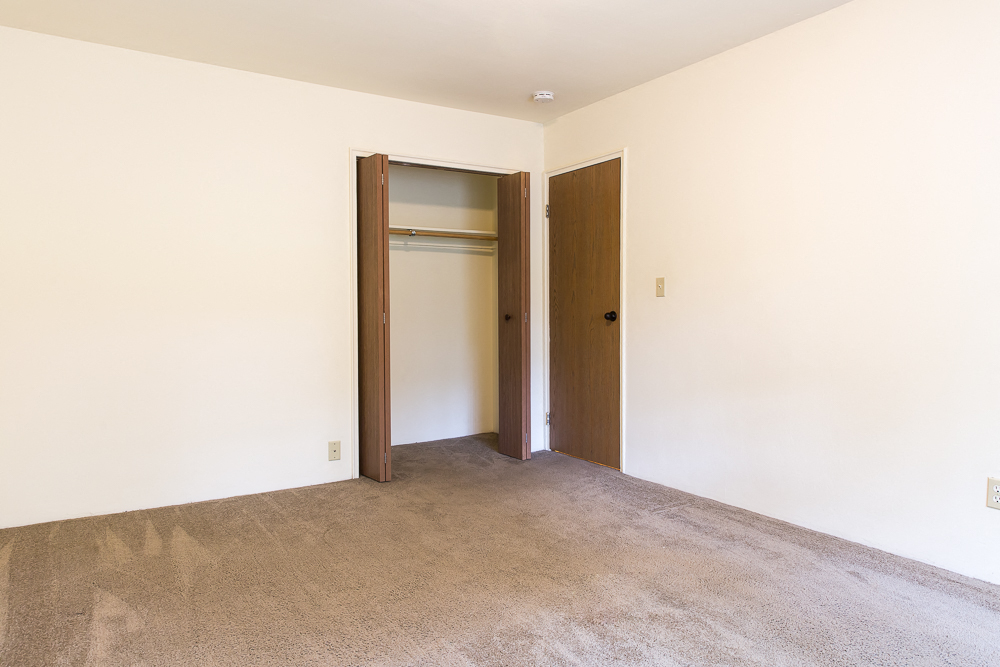 an empty room with a carpeted floor and two doors
