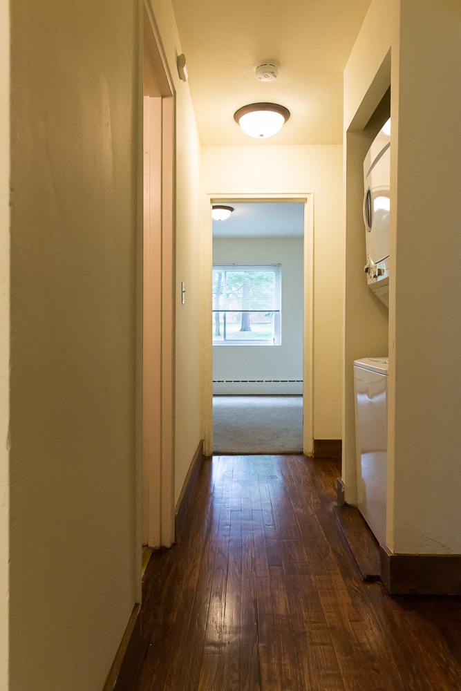 a hallway with wood floors and a closet with a window