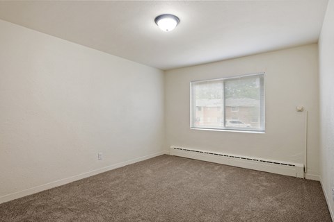 A room with a window and carpeted floor.